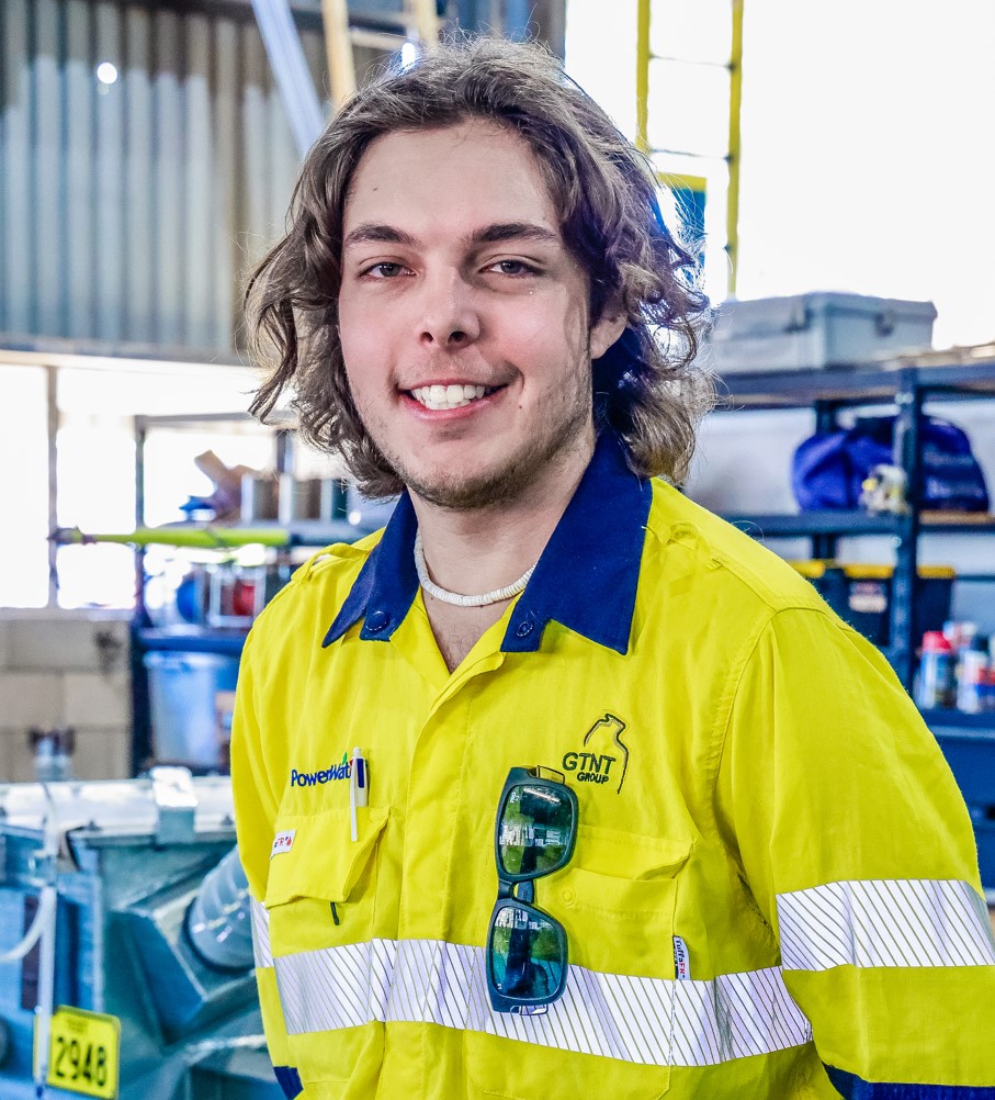 A smiling line worker apprentice wearing a Power and Water personl protective equipment.
